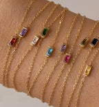 Waterproof gold necklaces with colorful glass stones on a wrist.