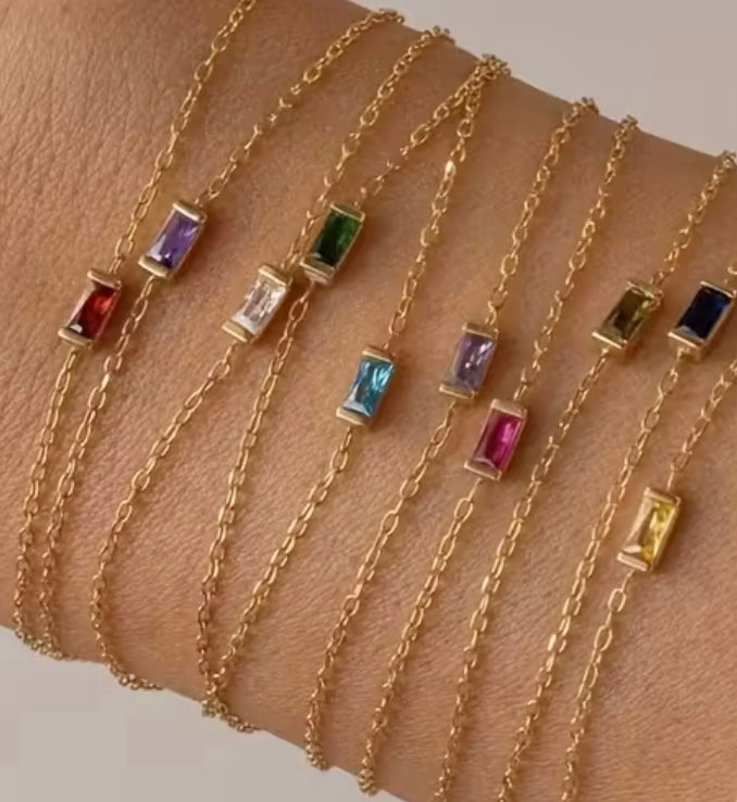Waterproof gold necklaces with colorful glass stones on a wrist.