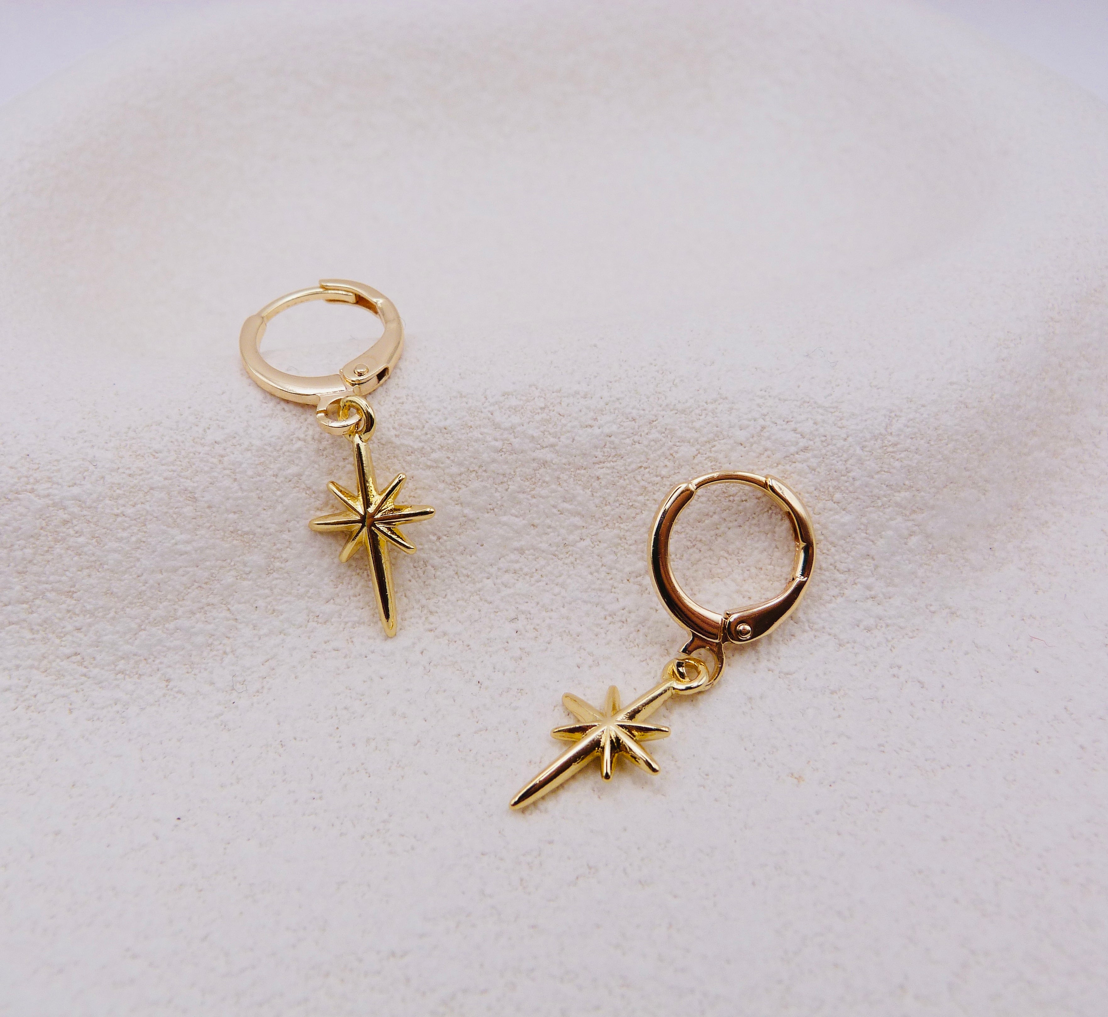 Gold hoop earrings with star-shaped charms.