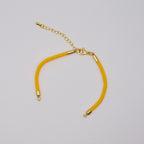 Yellow bracelet with gold clasp on a light gray background