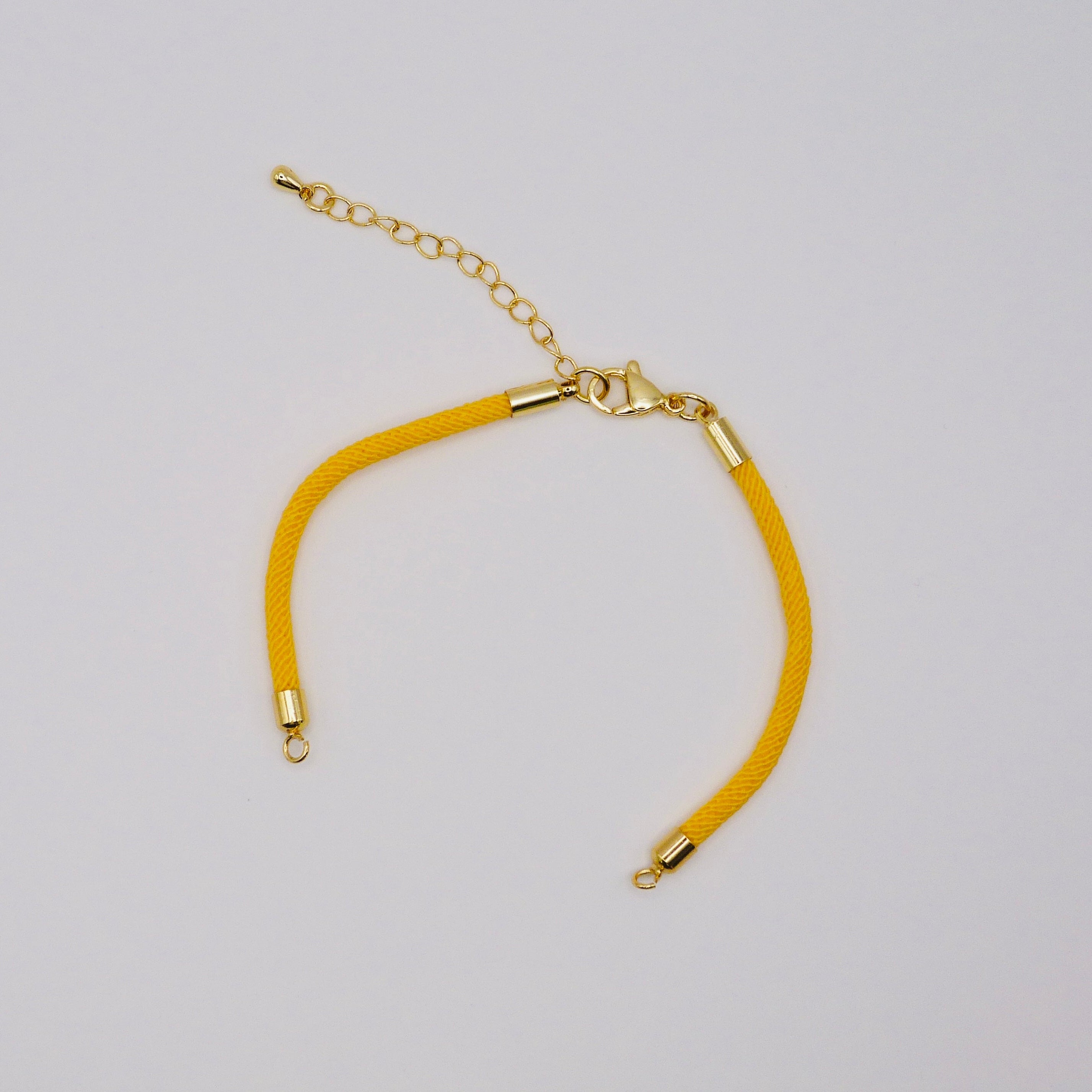 Yellow bracelet with gold clasp on a light gray background