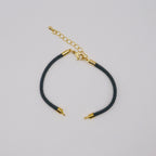 Black cord bracelet with gold accents on a light gray background