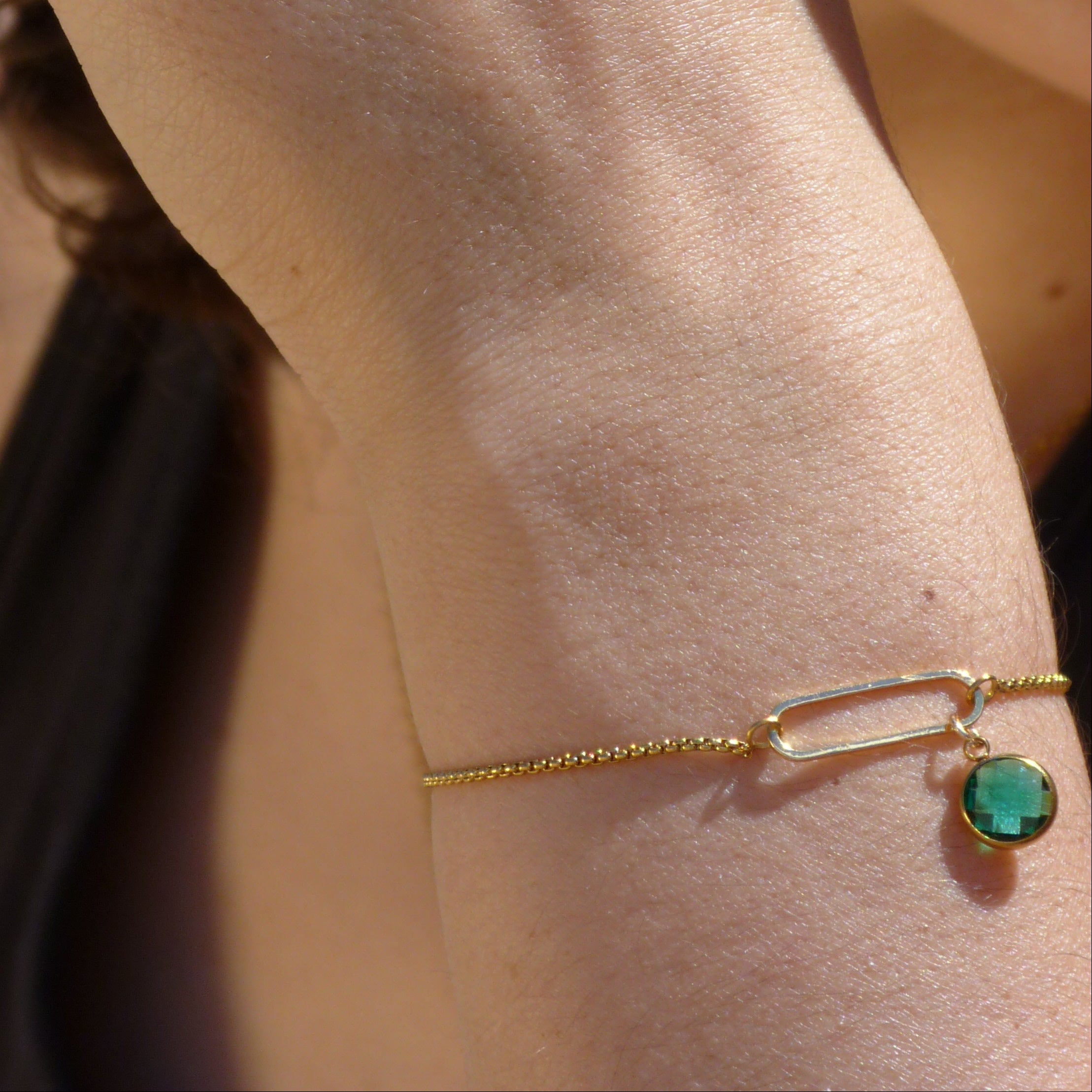 Close-up of a person's hand wearing a gold ring and bracelet with a blurred background