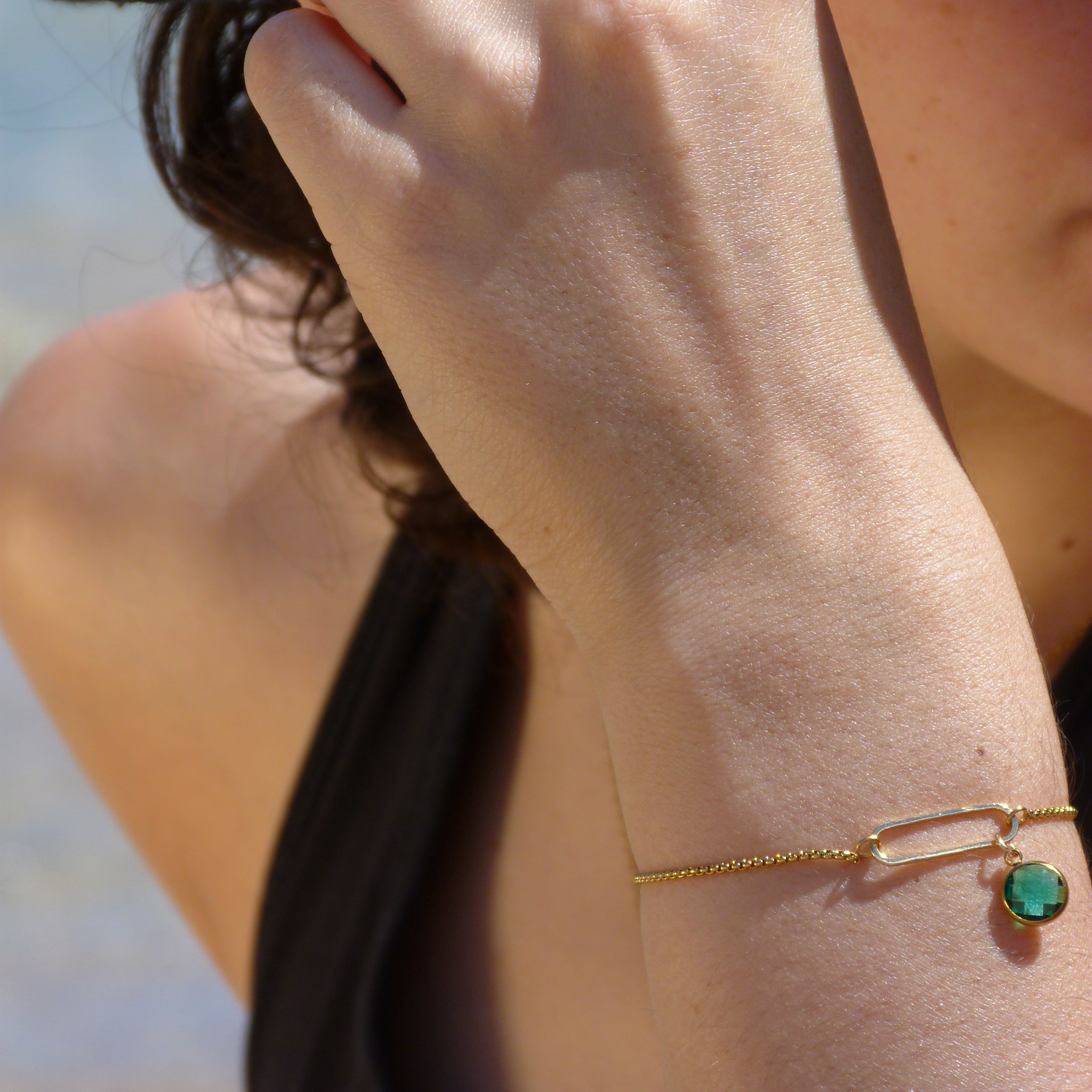 Close-up of a person's hand wearing a gold ring and bracelet with a blurred background