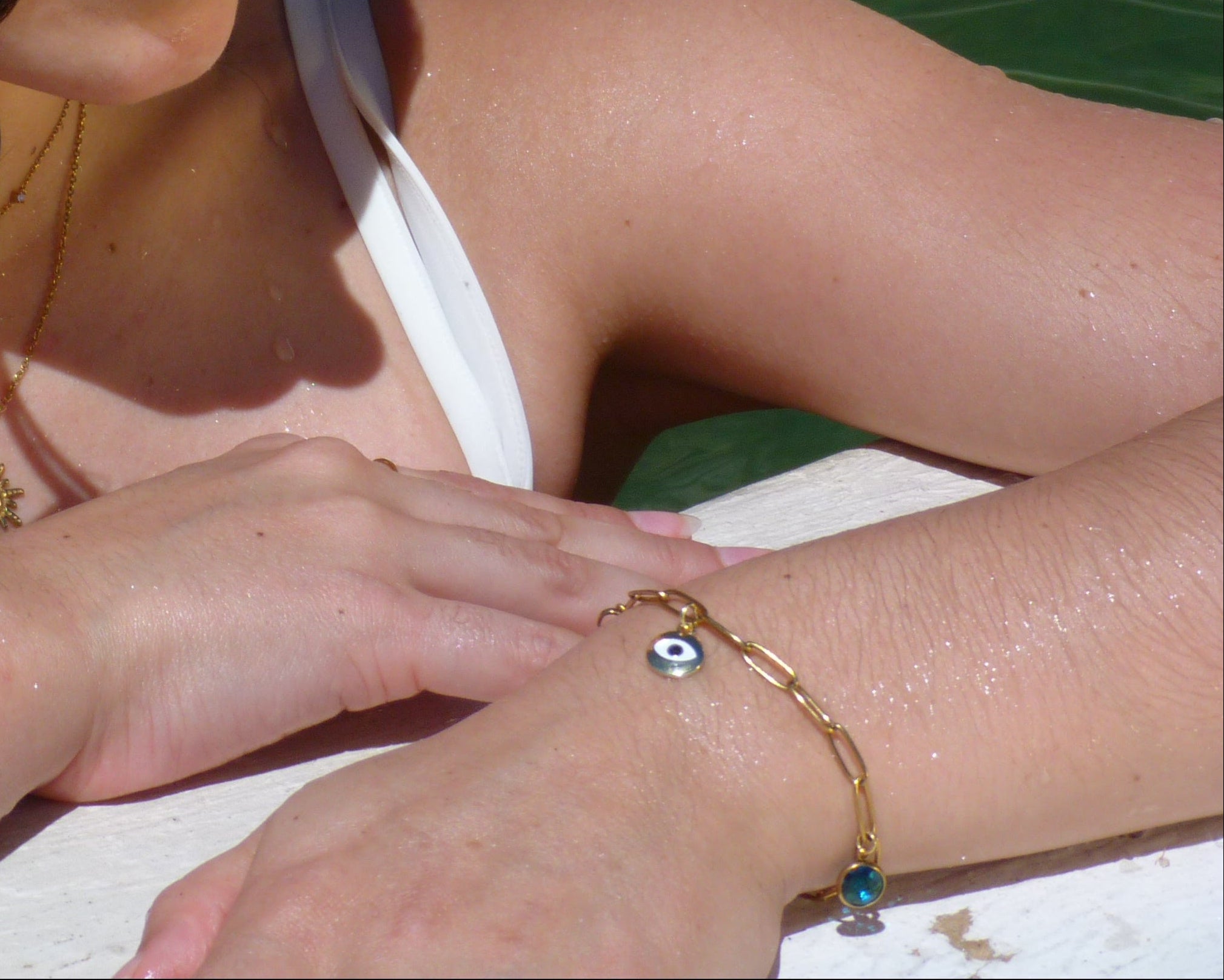 Gold paperclip bracelet with evil eye charm, and blue glass charm.