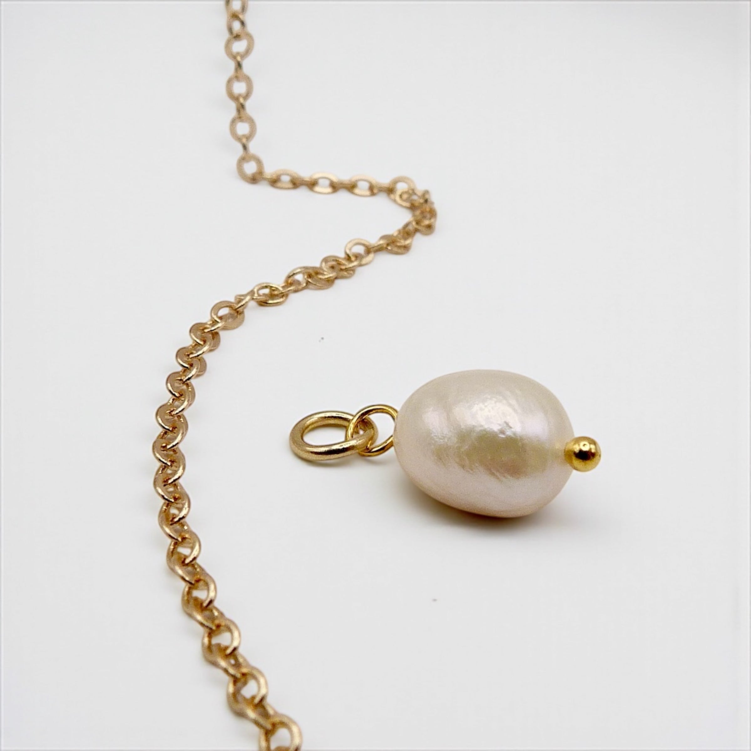 Gold chain with a pearl pendant on a white background